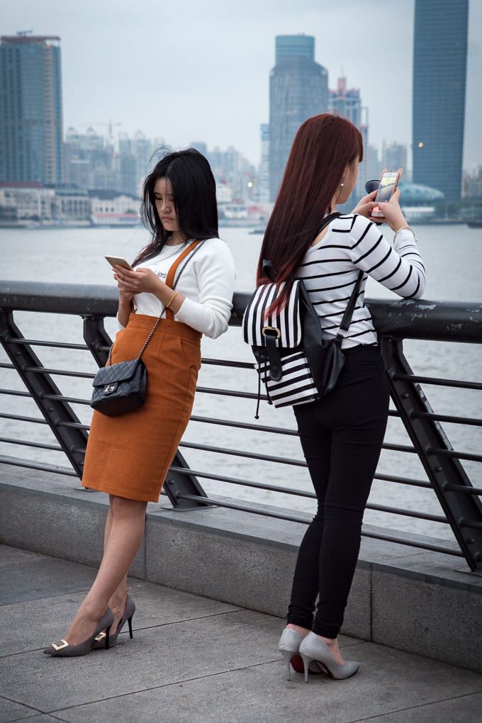 Women texting at The Bund, Shanghai, China