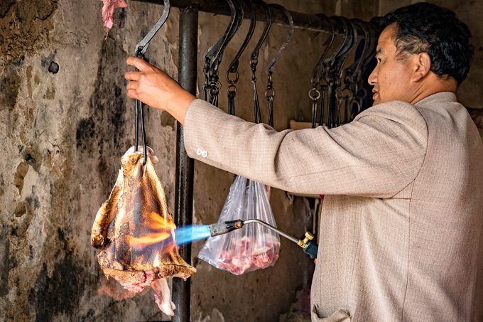 Butcher torching meat in Zhangjiajie, China