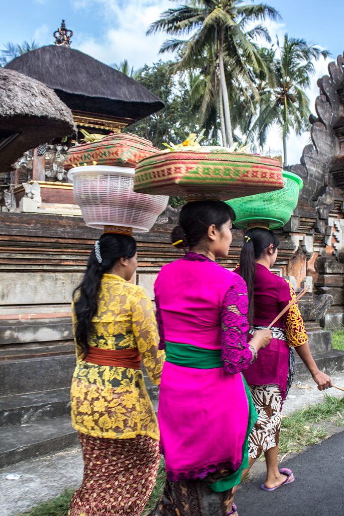 Balinese women carrying baskets on their heads, walking through Bali