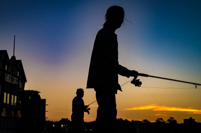 Fisherman and woman at dusk on Darling Harbour, Syndey, Australia