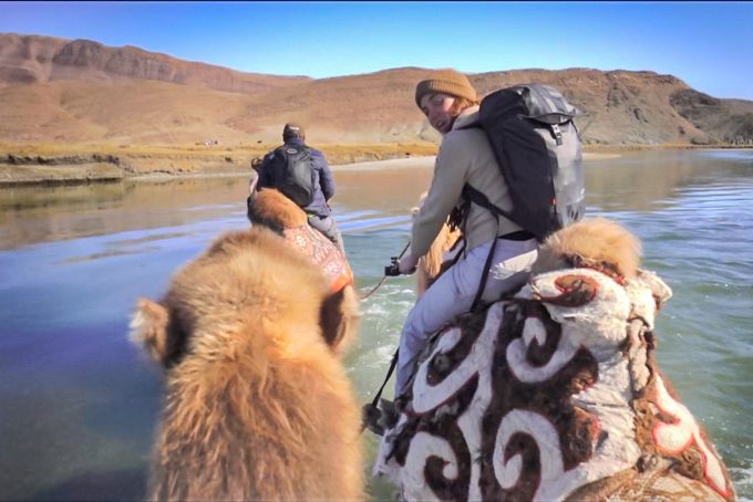Ansley Sawyer riding on a camel across river in Mongolia