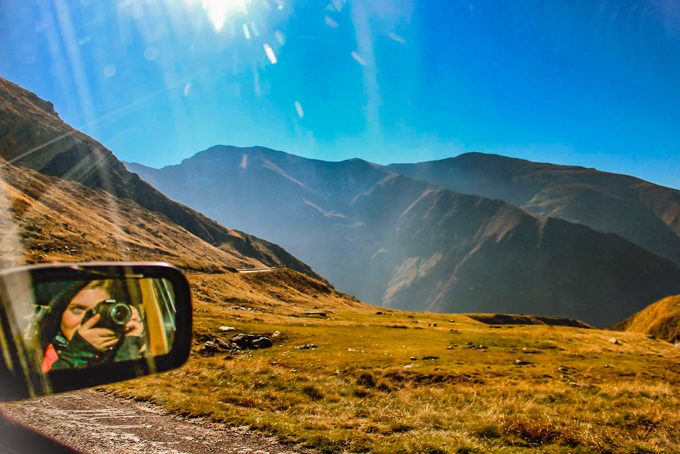 Ansley Sawyer reflected in a car mirror while driving through mountains in Mongolia