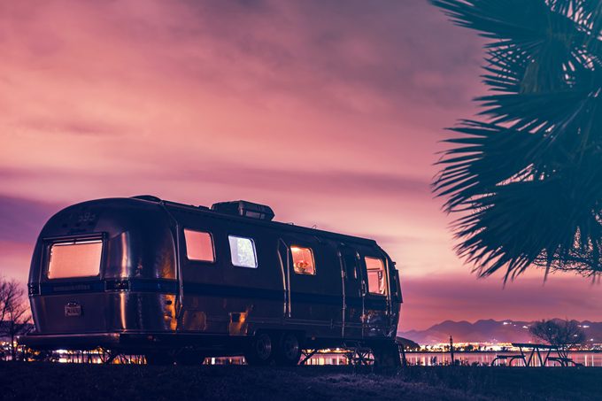Global Girl Travels Airstream parked on a lake in California at sunset